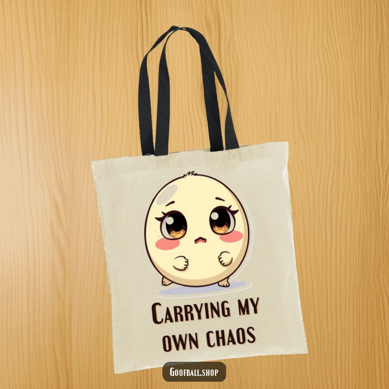 Funny tote bag featuring a small, round creature with mismatched eyes tripping, looking surprised, perfect for carrying essentials humorously.